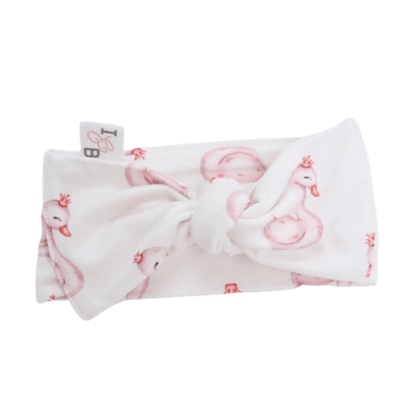 Isla and Bos Bamboo headwrap in Swan Princess, a white background with pink swans wearing crowns. A stylish and comfortable accessory for any baby, perfect for any occasion. Made from eco-friendly bamboo material.